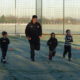 Footballers running on the MUGA in snow.
